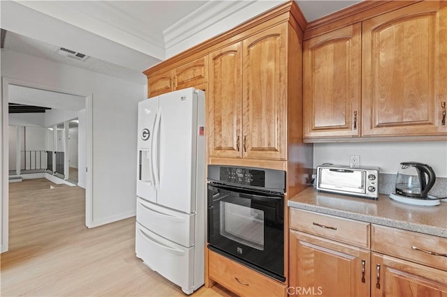 kitchen featuring black oven, white fridge with ice dispenser, light hardwood / wood-style floors, crown molding, and light stone countertops