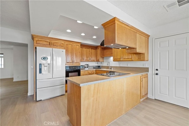 kitchen featuring sink, a textured ceiling, kitchen peninsula, light hardwood / wood-style floors, and black appliances