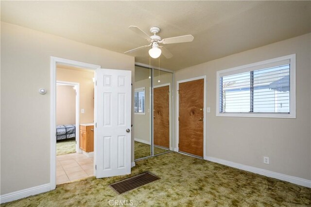 unfurnished bedroom featuring two closets, light colored carpet, and ceiling fan