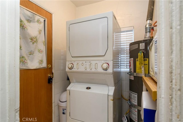 laundry room with water heater and stacked washing maching and dryer