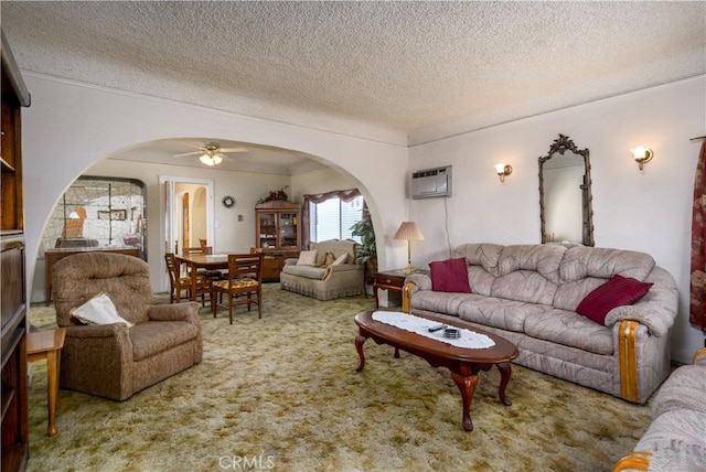 carpeted living room featuring ceiling fan, a wall mounted AC, and a textured ceiling