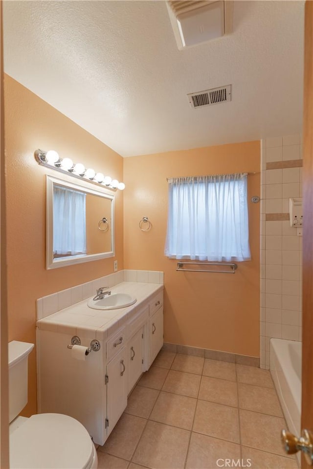 bathroom with visible vents, toilet, tile patterned floors, vanity, and a bath