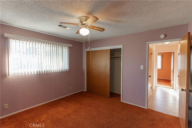 unfurnished bedroom with light carpet, a textured ceiling, visible vents, and a closet