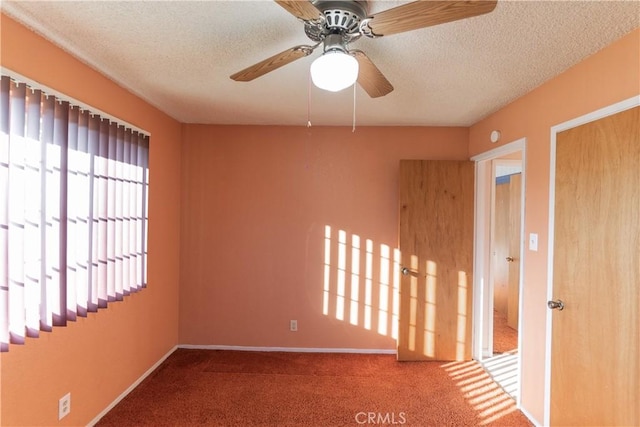 carpeted empty room with a wealth of natural light, ceiling fan, and a textured ceiling