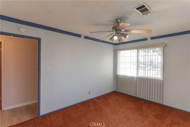 carpeted empty room with a textured ceiling, ornamental molding, visible vents, and a ceiling fan