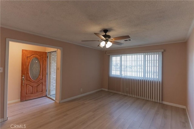 foyer entrance with crown molding, light wood finished floors, visible vents, ceiling fan, and baseboards