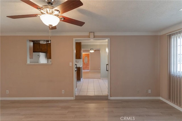 unfurnished room with baseboards, ceiling fan, ornamental molding, a textured ceiling, and light wood-type flooring