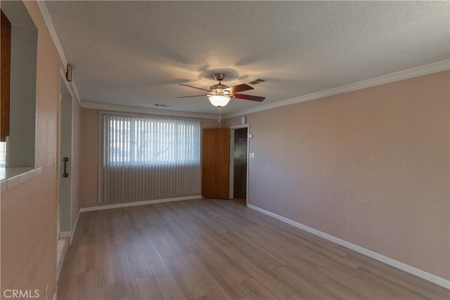 empty room featuring light wood finished floors, baseboards, visible vents, a textured ceiling, and crown molding