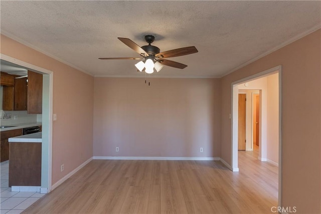 spare room with a textured ceiling, light wood-type flooring, baseboards, and crown molding