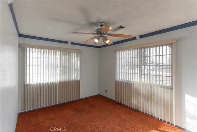 carpeted empty room featuring visible vents, crown molding, a textured ceiling, and ceiling fan