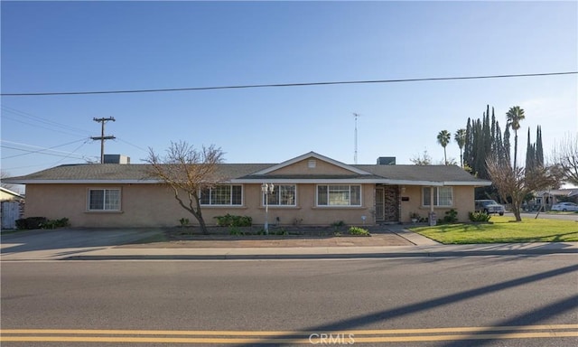 ranch-style home featuring a front lawn and stucco siding