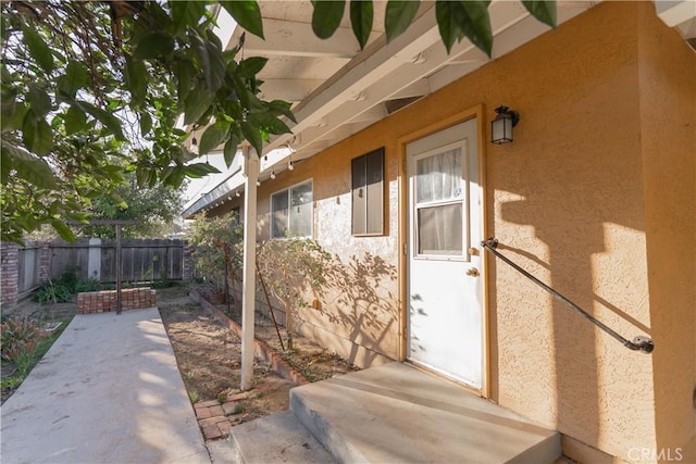 property entrance featuring a patio area, fence, and stucco siding