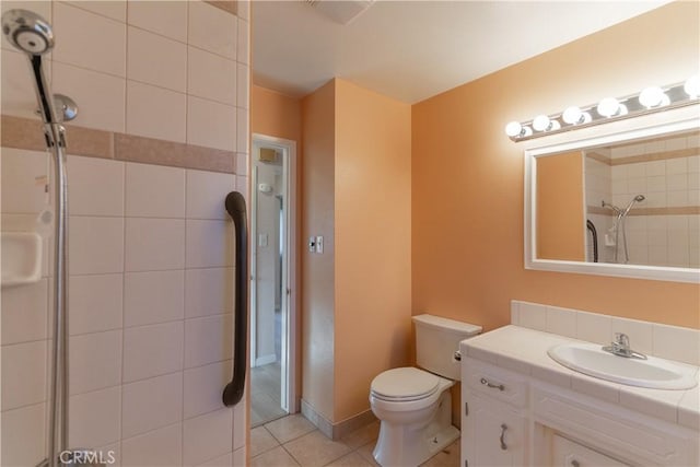 bathroom with tile patterned flooring, toilet, vanity, baseboards, and a shower