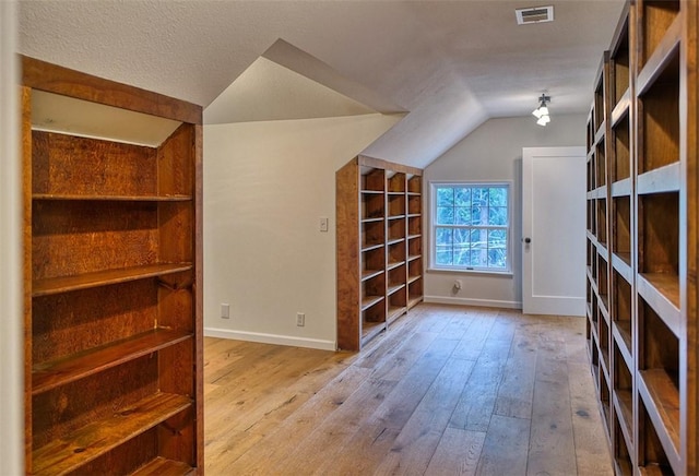 bonus room with vaulted ceiling, light hardwood / wood-style flooring, and a textured ceiling