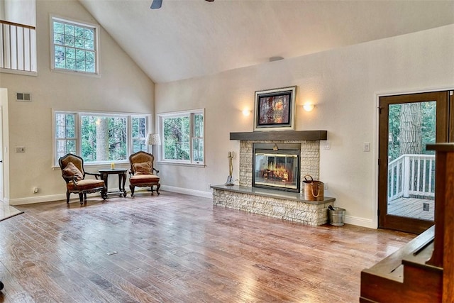 living room with a stone fireplace, a healthy amount of sunlight, hardwood / wood-style floors, and ceiling fan