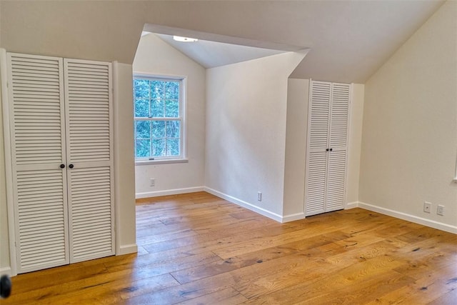 unfurnished bedroom featuring light hardwood / wood-style floors, vaulted ceiling, and a closet