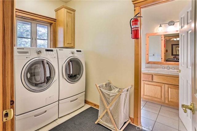 clothes washing area with cabinets, light tile patterned flooring, sink, and washing machine and clothes dryer