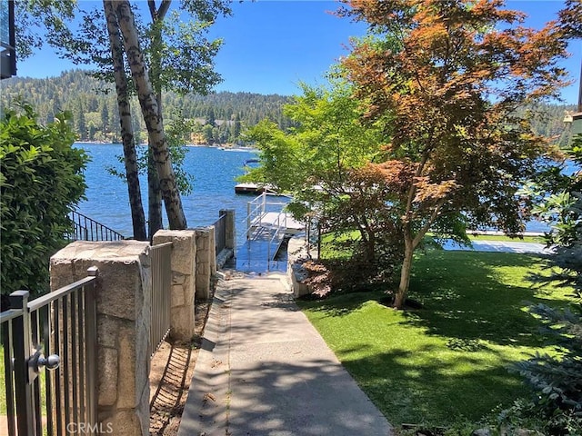 view of dock with a water view and a yard