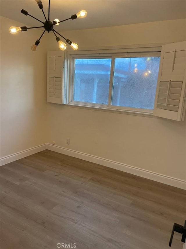 unfurnished room with a notable chandelier and dark wood-type flooring