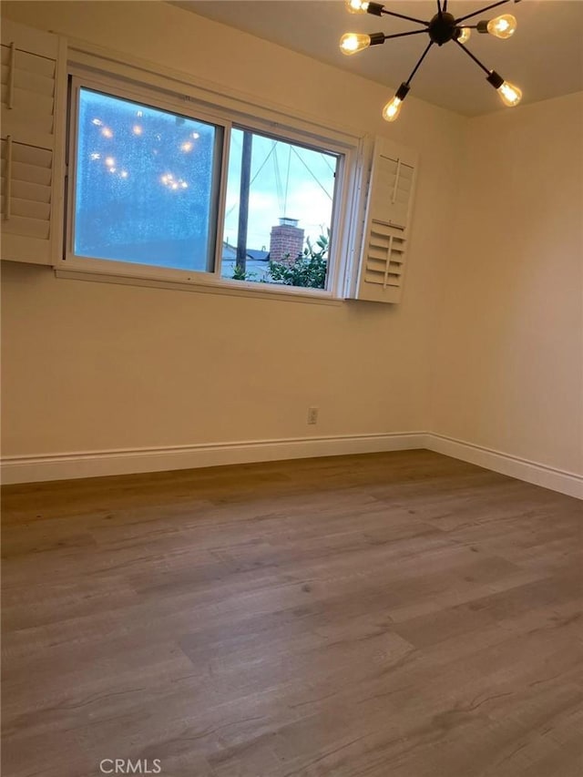 spare room with hardwood / wood-style flooring and a chandelier