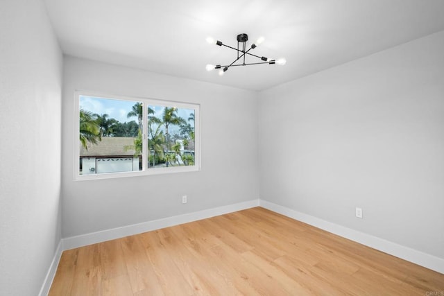 unfurnished room with hardwood / wood-style floors and a notable chandelier