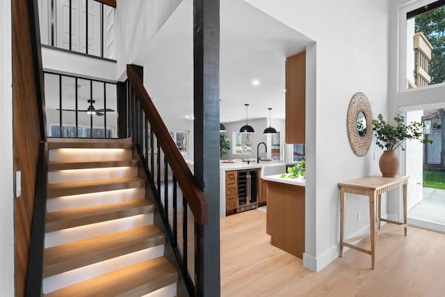 stairs with hardwood / wood-style floors, a wealth of natural light, and beverage cooler