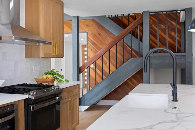 kitchen featuring stainless steel appliances, tasteful backsplash, light stone countertops, and wall chimney exhaust hood