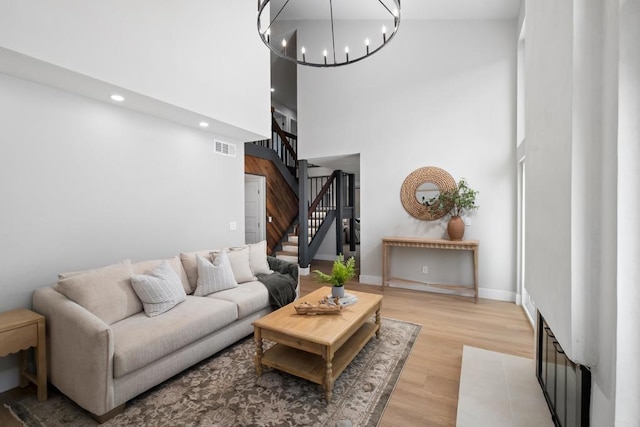 living room featuring an inviting chandelier, a towering ceiling, and light hardwood / wood-style floors