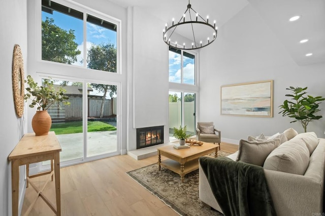 living room featuring a notable chandelier, a towering ceiling, and light hardwood / wood-style floors