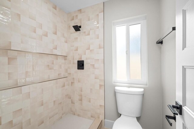 bathroom with a tile shower and toilet