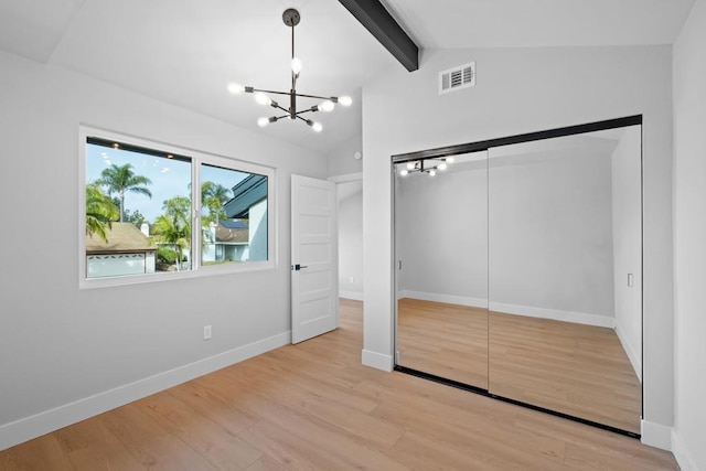 unfurnished bedroom featuring a closet, vaulted ceiling with beams, an inviting chandelier, and light hardwood / wood-style flooring