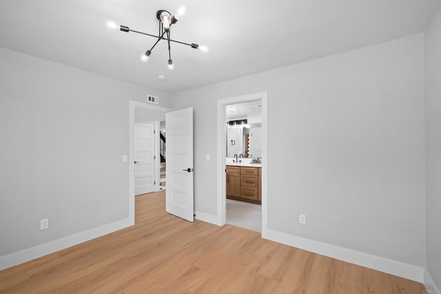 unfurnished bedroom with sink, light hardwood / wood-style floors, a chandelier, and ensuite bathroom