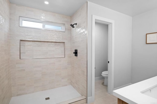 bathroom featuring vanity, tiled shower, tile patterned floors, and toilet