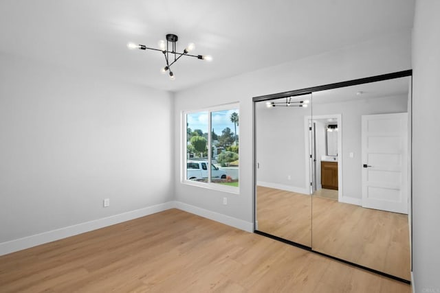 unfurnished bedroom with hardwood / wood-style flooring and a chandelier