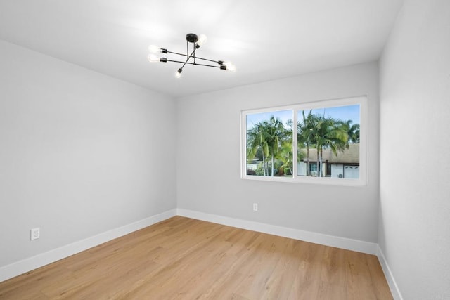 empty room featuring a chandelier and hardwood / wood-style floors