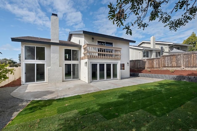 rear view of house with a patio area, a balcony, and a lawn