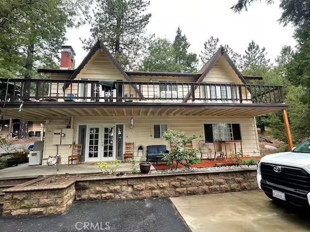 rear view of house with a patio, french doors, and a balcony