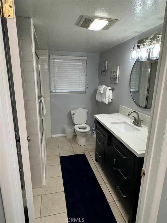 bathroom featuring vanity, a shower with shower door, tile patterned flooring, and a textured ceiling