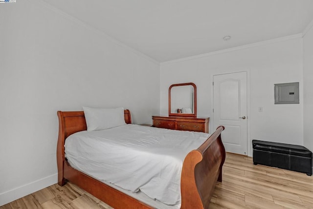 bedroom featuring ornamental molding, electric panel, and light wood-type flooring