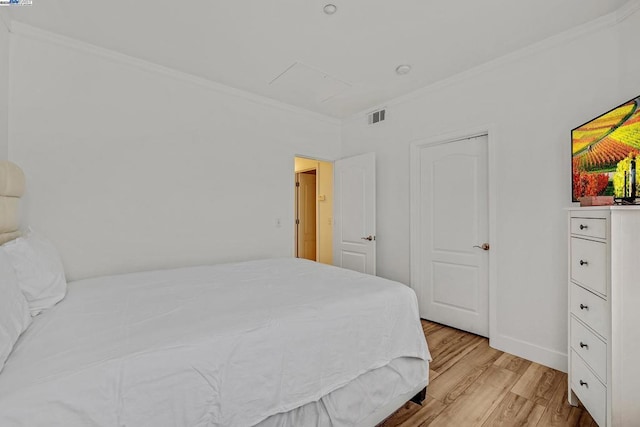 bedroom with ornamental molding and light wood-type flooring