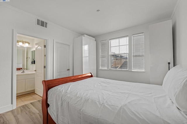 bedroom featuring ornamental molding, ensuite bathroom, and light wood-type flooring