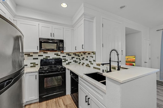 kitchen featuring ornamental molding, white cabinets, light hardwood / wood-style floors, and black appliances