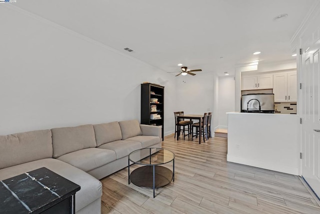 living room with crown molding, ceiling fan, and light hardwood / wood-style floors