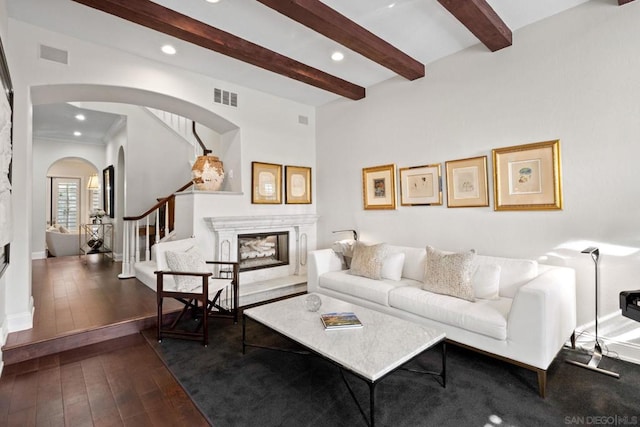 living room featuring dark hardwood / wood-style floors, a premium fireplace, and beam ceiling