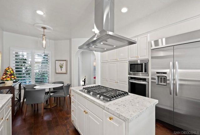 kitchen with pendant lighting, dark wood-type flooring, built in appliances, island range hood, and white cabinets