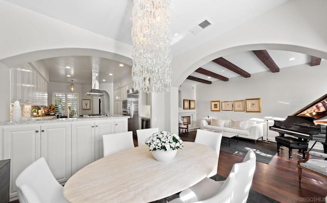 dining area featuring an inviting chandelier, dark wood-type flooring, and beamed ceiling