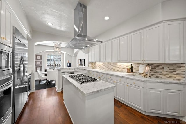 kitchen featuring stainless steel appliances, island exhaust hood, white cabinets, a kitchen island, and kitchen peninsula