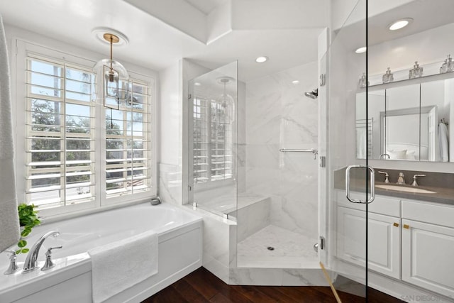 bathroom featuring hardwood / wood-style flooring, plus walk in shower, and vanity