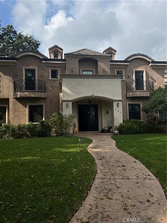 view of front facade featuring a front lawn and a balcony