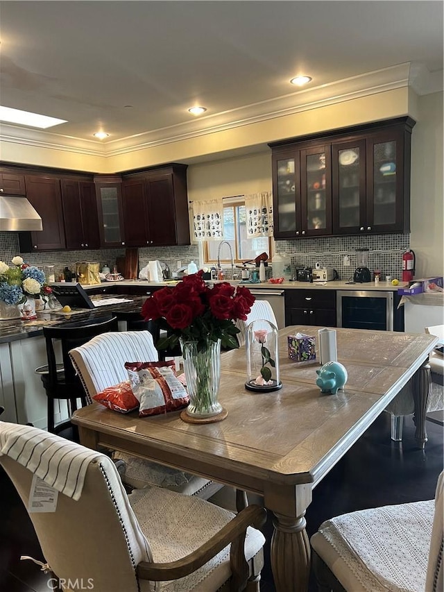 kitchen featuring backsplash, ornamental molding, dark brown cabinetry, and exhaust hood